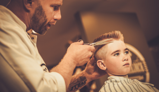 A man cutting another mans hair with scissors.