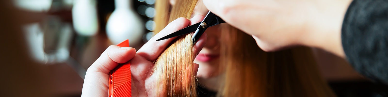 A woman cutting her hair with scissors.