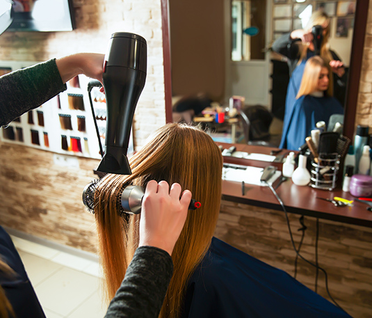 A woman blow drying her hair in a salon.