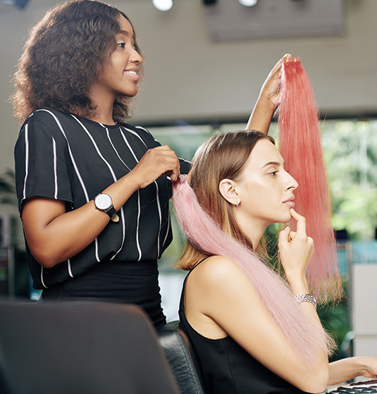 A woman is getting her hair done by another person.