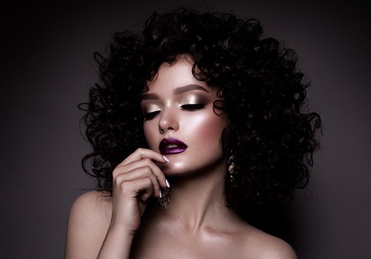 A woman with curly hair and purple lipstick.