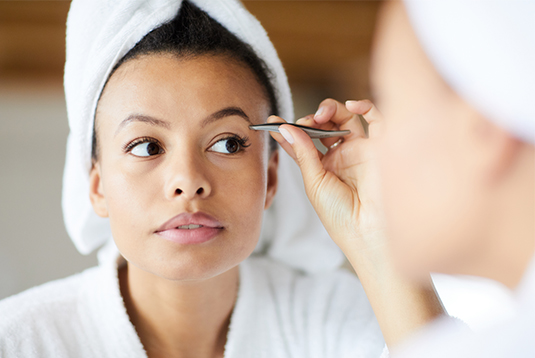 A woman is looking at her reflection in the mirror.