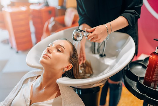 A woman getting her hair washed in a sink