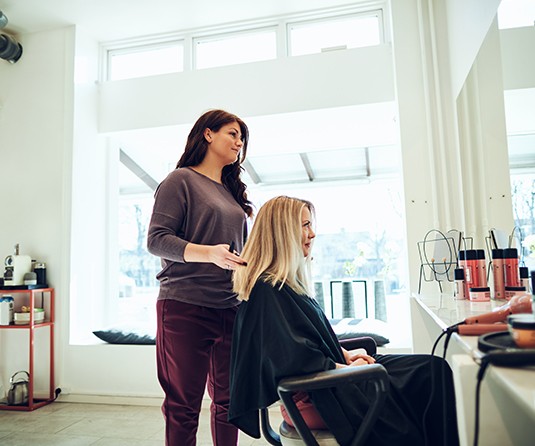 A woman getting her hair done by another person.