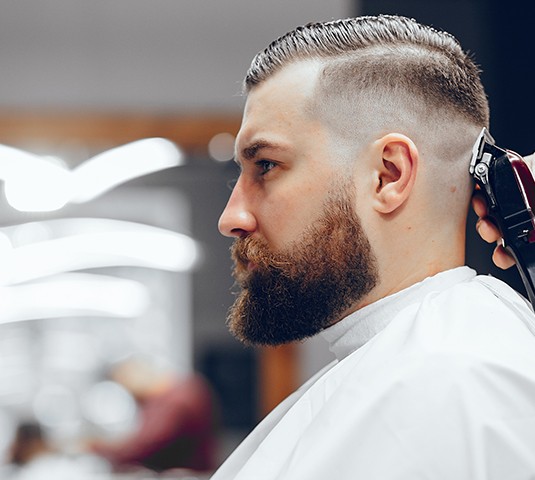 A man getting his hair cut by another person