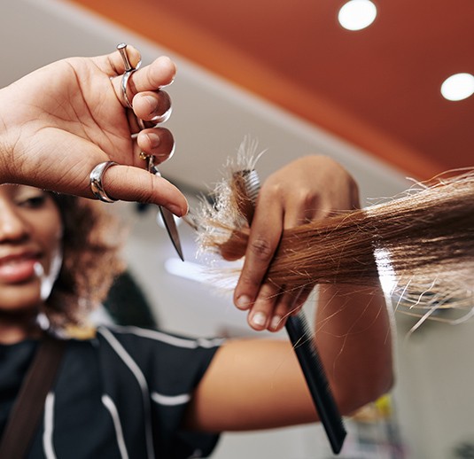 A woman cutting her hair with scissors.