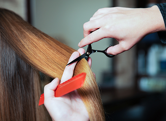 A person cutting another person 's hair with scissors.