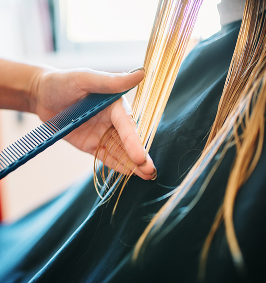 A person cutting their hair with scissors and comb.