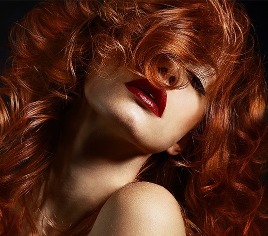 A woman with red hair and lipstick on her lips.