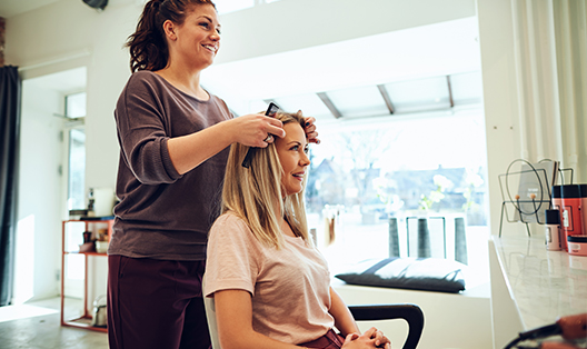 A woman getting her hair done by another person.