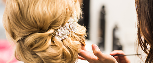 A woman with blonde hair is holding her hand up to the side of her head.